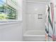 Bright bathroom featuring a tub with white tiled surround and convenient built-in shelf at 3210 Roseheath Ln, Lithonia, GA 30038