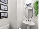Modern half bath featuring a pedestal sink, sleek black fixtures, and stylish wall art at 3977 Fox Glen Dr, Woodstock, GA 30189