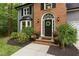 Inviting front entrance with a black door, brick accents, and professionally landscaped plants at 4806 Deer Chase, Powder Springs, GA 30127