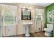 Traditional bathroom with pedestal sink, decorative mirror, and natural light from the windows at 265 Tamea Trl, Covington, GA 30014