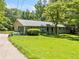 Exterior view of a brick home featuring a lush front yard and mature tree providing ample shade at 265 Tamea Trl, Covington, GA 30014