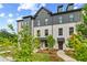 View of a modern white brick townhome with a gray roof and professionally landscaped front yard at 445 Breccia Run, Mcdonough, GA 30253