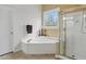 Bathroom showcasing a white soaking tub, a tiled shower, and a decorative window at 6772 Blantyre Boulevard Blvd, Stone Mountain, GA 30087