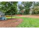 Large backyard with lush lawn, mature trees, play equipment, and a wooden privacy fence at 1055 Delmont Ter, Roswell, GA 30075