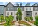 Charming townhome exterior with brick facade, black trim, landscaped yard, and inviting walkways under a partly cloudy sky at 441 Breccia Run, Mcdonough, GA 30253