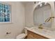 Updated half bath boasts a wood vanity with marble countertop and gold fixtures at 315 N Fayette Dr, Fayetteville, GA 30214
