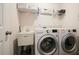 Well-equipped laundry room with modern washer and dryer, utility sink, and storage shelves at 383 Crestbrook Ln, Dallas, GA 30157