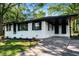 Front exterior with freshly painted white facade, mature trees, and a long driveway leading to a carport at 1207 Ellington Dr, Morrow, GA 30260