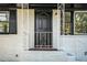 A welcoming front porch with a black front door, white decorative railings and freshly painted white brick at 1207 Ellington Dr, Morrow, GA 30260