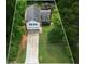 An aerial view highlights this house and its landscaped yard, nestled amidst the vibrant greenery of mature trees at 4255 Hidden Meadow Circle, Sugar Hill, GA 30518