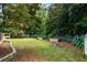 A lush backyard with a fire pit, garden beds, a wooded area, and stone retaining wall features at 4255 Hidden Meadow Circle, Sugar Hill, GA 30518