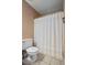 Cozy bathroom featuring neutral tiling, a white toilet, and shower with a decorative white curtain at 4255 Hidden Meadow Circle, Sugar Hill, GA 30518
