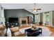 Open living room featuring a stone fireplace, hardwood floors, a ceiling fan, and many windows at 4255 Hidden Meadow Circle, Sugar Hill, GA 30518