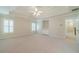 Carpeted bedroom with tray ceiling, ceiling fan, built-in shelves, and hallway access at 4610 Admiral Ridge Way, Lilburn, GA 30047