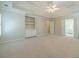 Carpeted main bedroom with tray ceiling, ceiling fan, built-in shelves, and bathroom access at 4610 Admiral Ridge Way, Lilburn, GA 30047