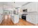 Modern kitchen with stainless steel appliances, white cabinetry, quartz countertops, and hardwood flooring at 110 Hogue St, Atlanta, GA 30312