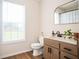Bathroom with modern fixtures, including a window, vanity, toilet, and decorative mirror at 409 Cold Springs Ln, Mcdonough, GA 30252