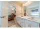 Bathroom featuring double sinks, gold hardware, and doorway to bedroom and bathtub area at 704 Stonecrest Ln, Loganville, GA 30052