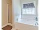 Bathroom features a large soaking tub, separate glass shower, and a window at 704 Stonecrest Ln, Loganville, GA 30052
