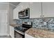Close up view of modern kitchen featuring granite countertops, stainless steel appliances, and stylish backsplash at 4421 Fulson Dr, Lilburn, GA 30047
