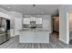 Well-lit kitchen with stainless steel appliances, large island, mosaic backsplash, and modern white cabinets at 4421 Fulson Dr, Lilburn, GA 30047
