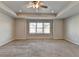 Spacious main bedroom featuring neutral carpet, large windows, a ceiling fan, and tray ceilings at 4421 Fulson Dr, Lilburn, GA 30047