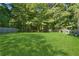 Large backyard with lush green grass, mature trees, and a wooden fence for privacy at 6223 Marbut Farms Ln, Lithonia, GA 30058