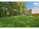 Large backyard with green grass, mature trees and a view of the back of the home at 6223 Marbut Farms Ln, Lithonia, GA 30058