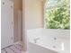 Bright bathroom features a large soaking tub with a garden window and separate shower stall at 7186 Raintree Loop, Jonesboro, GA 30236