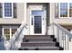 Close-up of the front door with sidelights, black shutters, and white railing leading up to the entrance at 7186 Raintree Loop, Jonesboro, GA 30236
