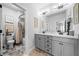 Bright bathroom featuring a double sink vanity, marble countertop, modern lighting and shower with floor-to-ceiling stone tile at 4440 Atwood Dr, Cumming, GA 30040
