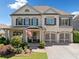 Charming two-story home with white brick, shuttered windows, two-car garage, and professionally landscaped front yard at 4440 Atwood Dr, Cumming, GA 30040