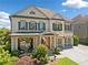 Charming two-story home with white brick, shuttered windows, two-car garage, and covered front porch at 4440 Atwood Dr, Cumming, GA 30040
