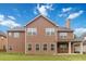 Two-story home back exterior featuring brown siding, multiple windows, and covered porch at 651 Deer Springs Way, Loganville, GA 30052