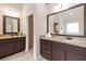 Double vanity bathroom with dark wood cabinets, granite countertops, and large mirrors at 651 Deer Springs Way, Loganville, GA 30052