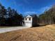A two-story home with gray siding, brick accents, and a two-car garage on a sunny lot surrounded by trees at 192 Paces Lakes Pt, Dallas, GA 30157