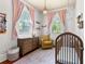 Bright bedroom featuring a wood crib with a dresser and a comfortable sitting chair at 429 Oakland Ave, Atlanta, GA 30312