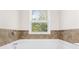 Bright bathroom with a white tub with chrome fixtures and tiled backsplash at 2957 Smith Ridge Trce, Peachtree Corners, GA 30071