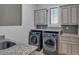 Well-lit laundry room with front-load washer and dryer and overhead cabinets for storage at 89 Somerset Ln, Cartersville, GA 30121
