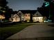 Nighttime view of an elegant home with landscape lighting accentuating architectural details and lush greenery at 965 Tiverton Ln, Alpharetta, GA 30022