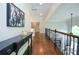 Open hallway on the second story with hardwood floors, and decorative console table at 965 Tiverton Ln, Alpharetta, GA 30022