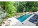 Aerial view of a backyard featuring a gorgeous in-ground pool with an outdoor firepit and lounge seating at 965 Tiverton Ln, Alpharetta, GA 30022
