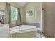 Bathroom featuring garden tub, glass enclosed shower with tile surround and neutral colored walls at 940 Planters Pl, Loganville, GA 30052