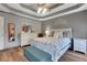 Bedroom featuring hardwood floors, tray ceiling, and modern furnishings at 940 Planters Pl, Loganville, GA 30052