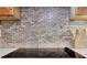 Close up of the updated kitchen backsplash is made of stone and the cooktop has a stylish black finish at 940 Planters Pl, Loganville, GA 30052