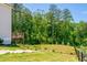 A lush backyard with a deck, bordered by trees and featuring wooden steps leading down the gentle slope at 1013 Liberty Springs Dr, Woodstock, GA 30188