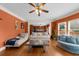 Open living room features hardwood floors, bright orange walls, a ceiling fan, and large windows for natural light at 3086 Frazier Walk, Decatur, GA 30033