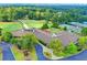 Aerial view showcasing the clubhouse with golf course and tennis courts in a wooded setting at 3070 Ascot Ln, Roswell, GA 30076