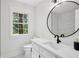 Bathroom featuring modern vanity, round mirror, and a window with a view of the outdoors at 4745 Elam Forest Dr, Stone Mountain, GA 30083