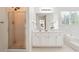 Bright bathroom featuring a shower, white cabinets and tub with decorative plant at 1624 Glenfield Dr, Lawrenceville, GA 30043